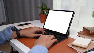Close up view of businessman hands typing keyboard of computer tablet at home office desk.