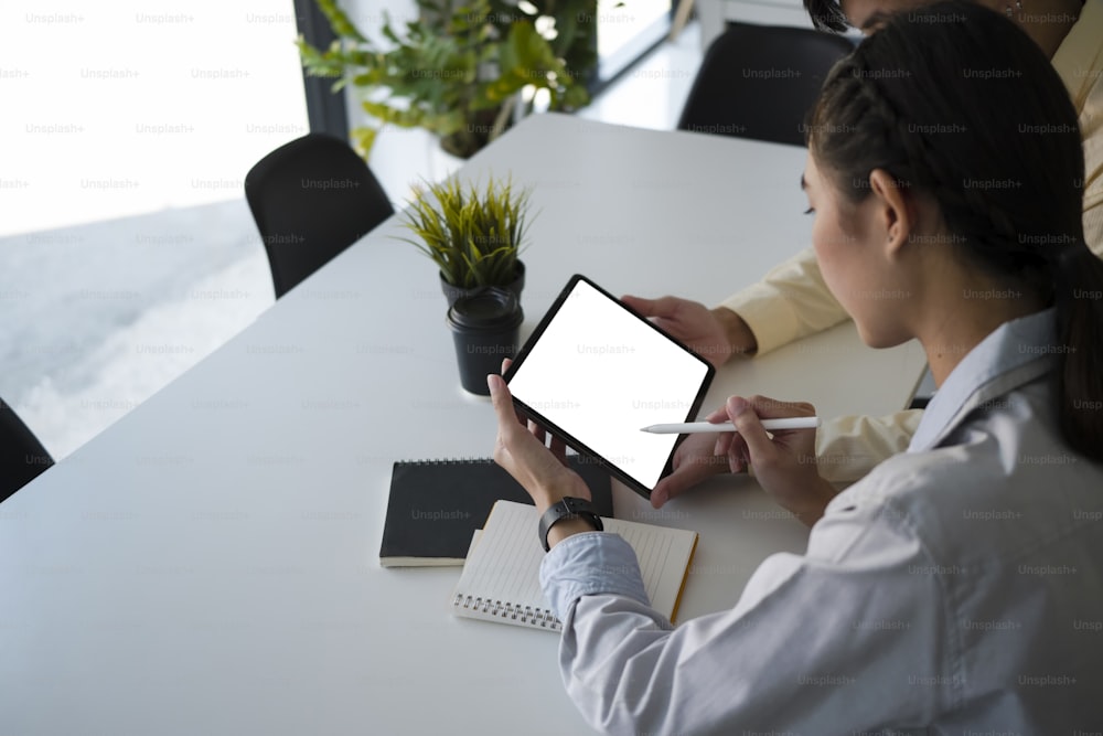 Jeunes hommes d’affaires travaillant sur une tablette numérique et discutant d’un projet financier au bureau.