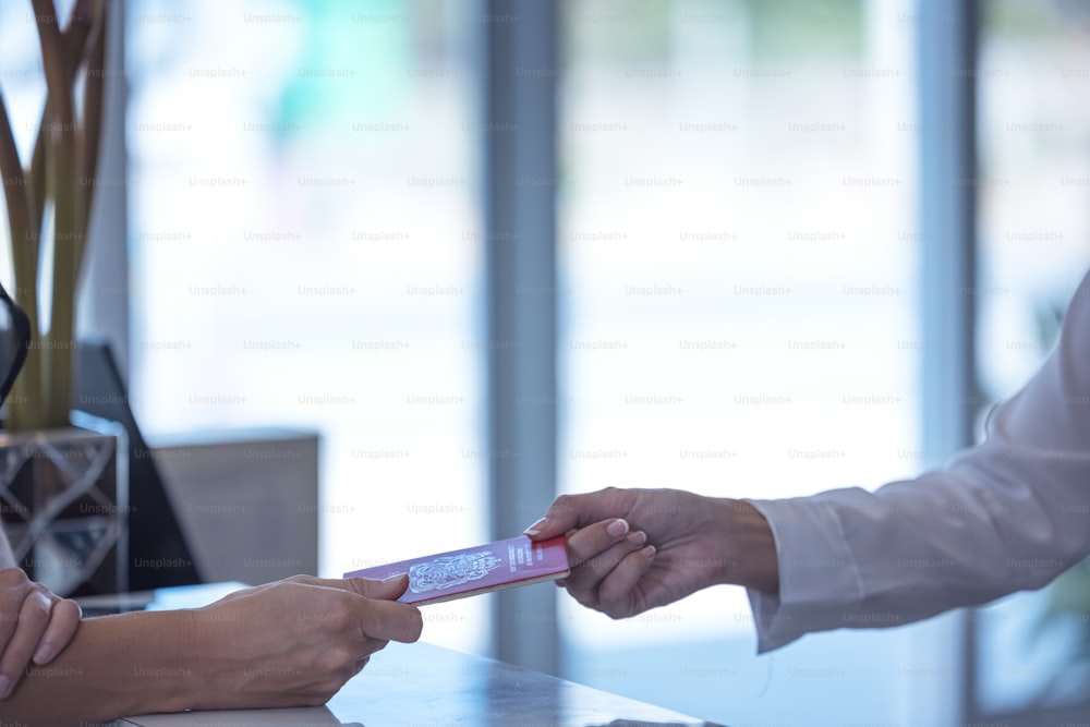 Recepcionista entrega un pasaporte a un turista en la recepción de un hostal