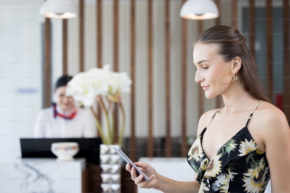 Smiling, confident, modern woman talking and checking social media at mobile phone in the hotel lobby