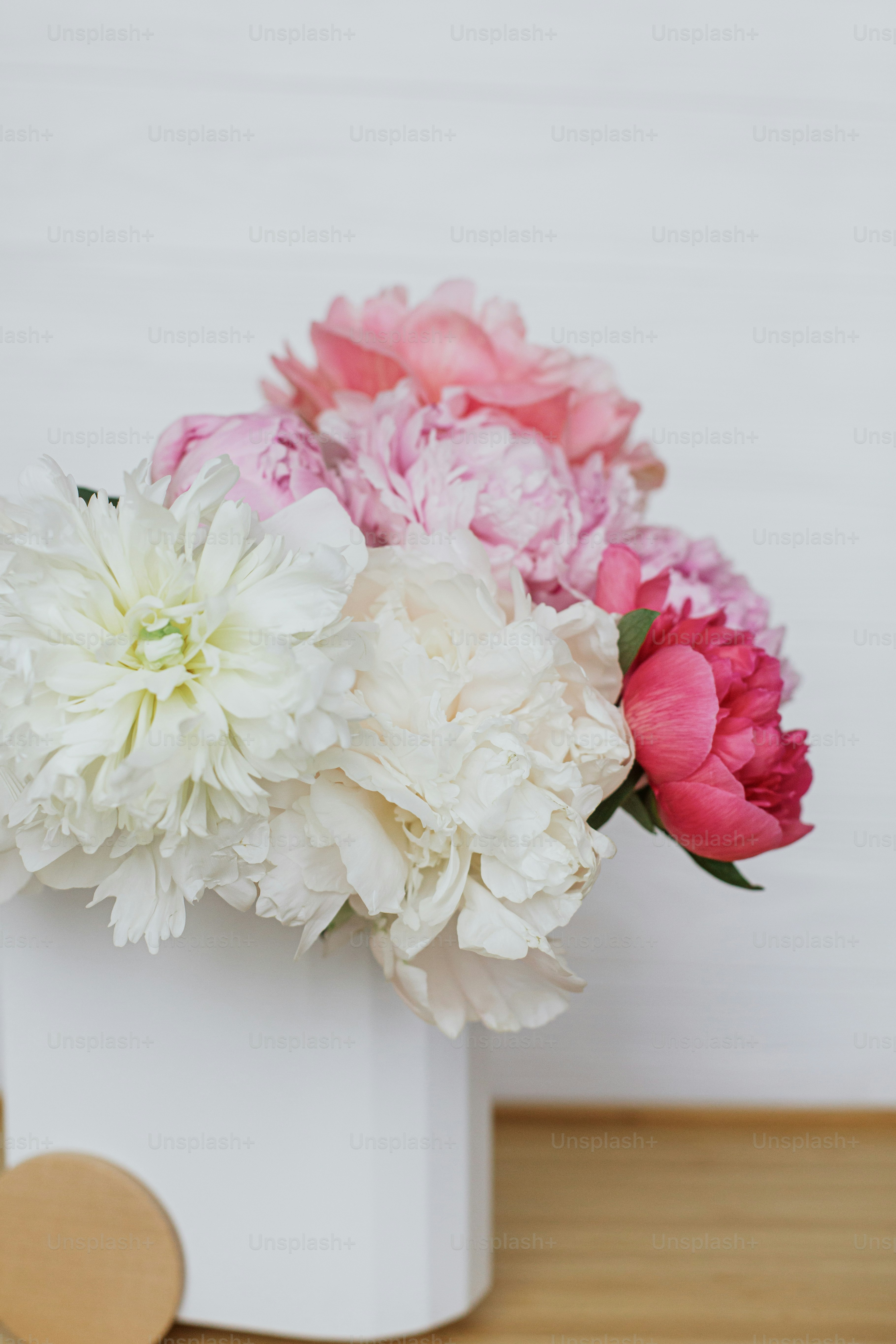 Beautiful peonies bouquet in modern stylish vase on white wooden background, copy space. Happy Mothers day. Womens day. Big pink and white peony flowers in room