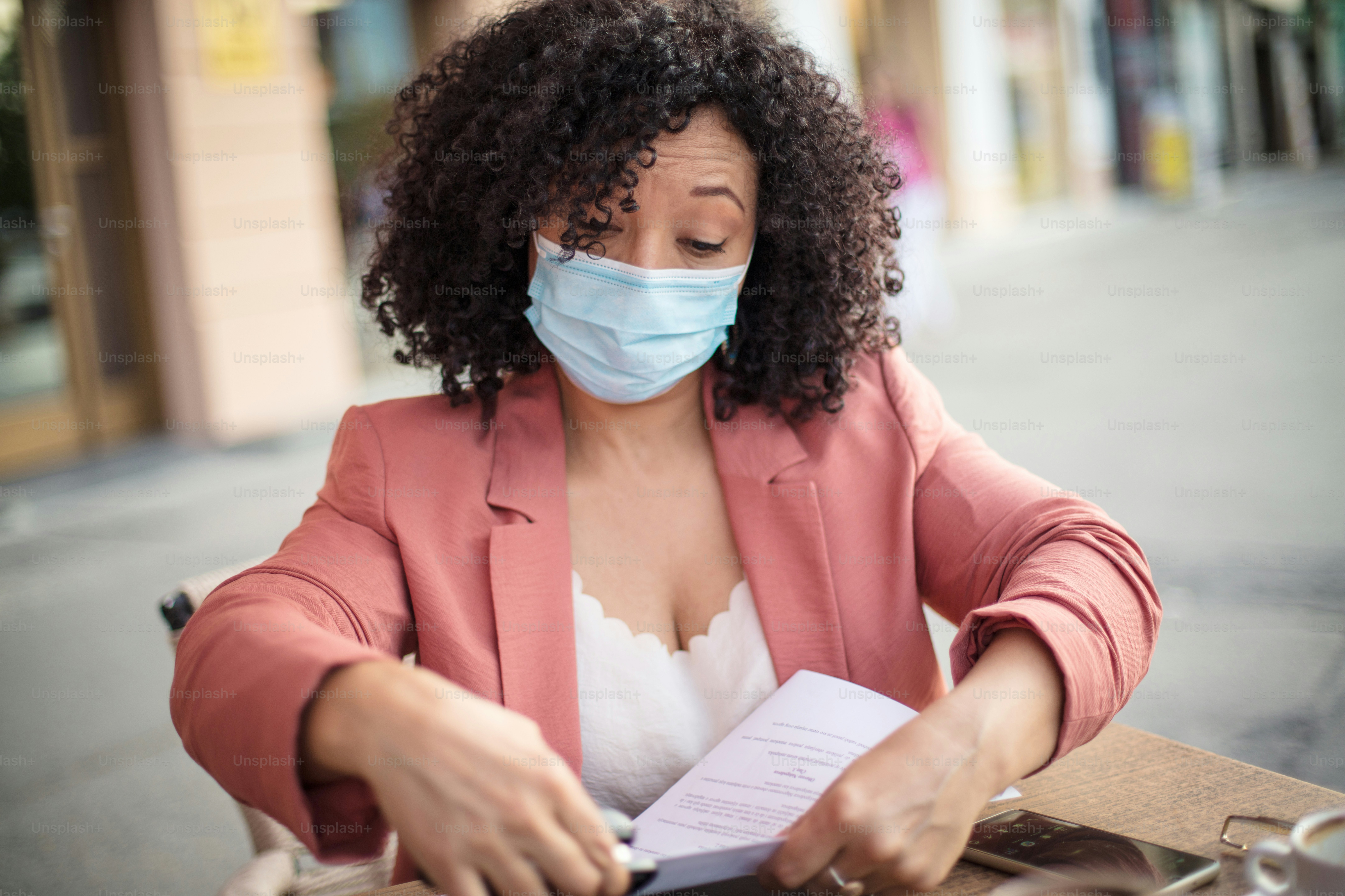 Solo trabajo.  Mujer de negocios con máscara protectora trabajando en documento en café.