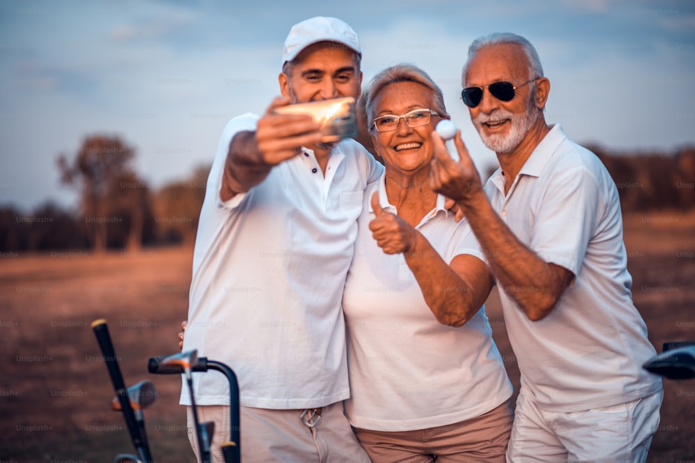 Golfisti anziani che usano il telefono e scattano autoritratti. L'attenzione è sullo sfondo.