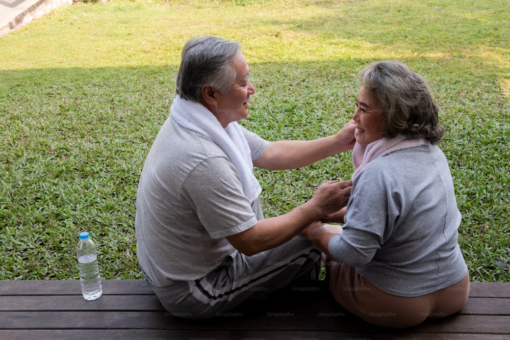 Happy Asian family exercising together at home. Senior couple drink water after do workout exercise together at home front yard in the morning. Retirement old age man and woman enjoy leisure activity at home