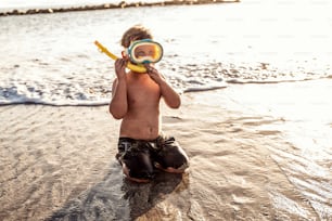 Vacation little boy in snorkeling mask having fun in water during summer holiday.