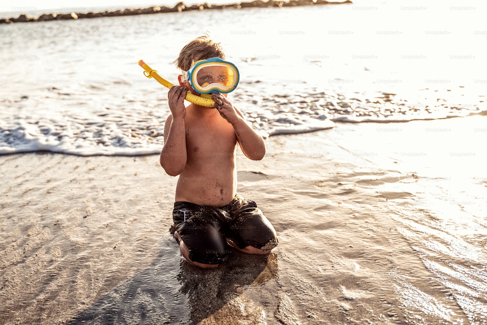 夏休みに水で楽しんでいるシュノーケリングマスクの休暇の小さな男の子。