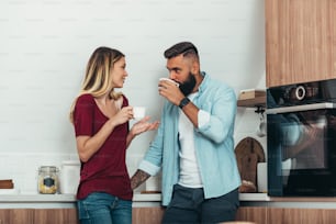 Young romantic couple drinking coffee in the morning while standing in the kitchen at home