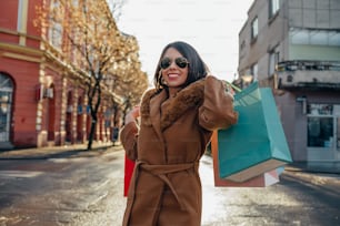 Jeune belle femme hispanique tenant des sacs à provisions lors d’une sortie en ville