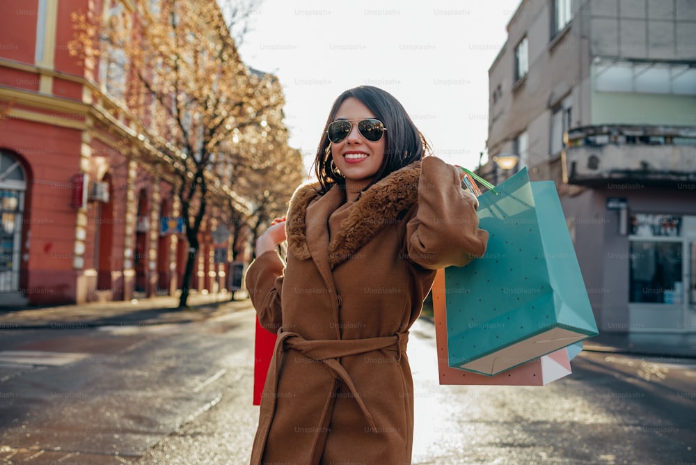Young beautiful hispanic woman holding shopping bags while out in a city