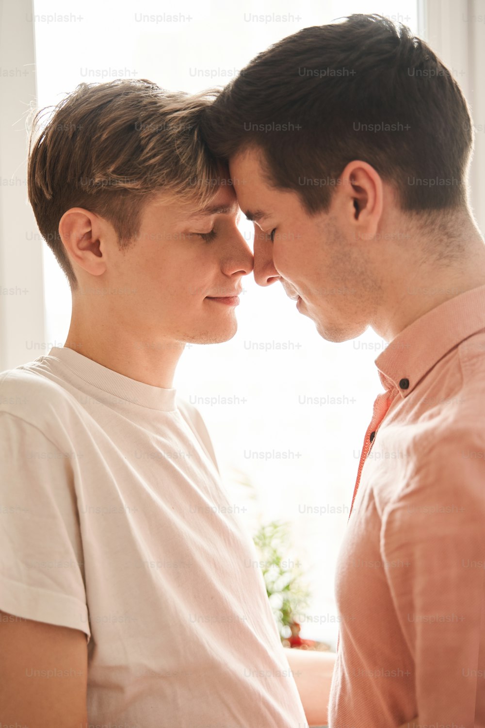 Lovely atmosphere. Close up of joyful young couple bonding to each other and showing true emotions while spending time at their kitchen. Homosexual relationships concept. Stock photo