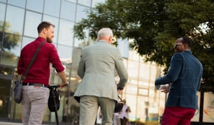 Three business man on street. Two men with electric scooter.