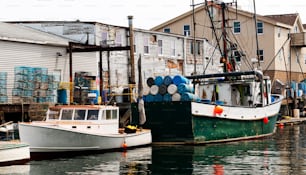色とりどりのロブスターの罠、ロープ、そして翌日海に戻る準備をするために必要なすべてのものを備えた建物の後ろに停泊している商業漁船。