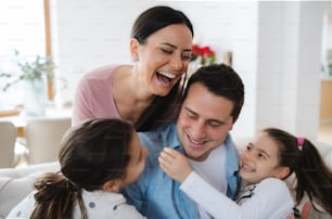 Portrait of cheerful parents with small daughters indoors at home, having fun.