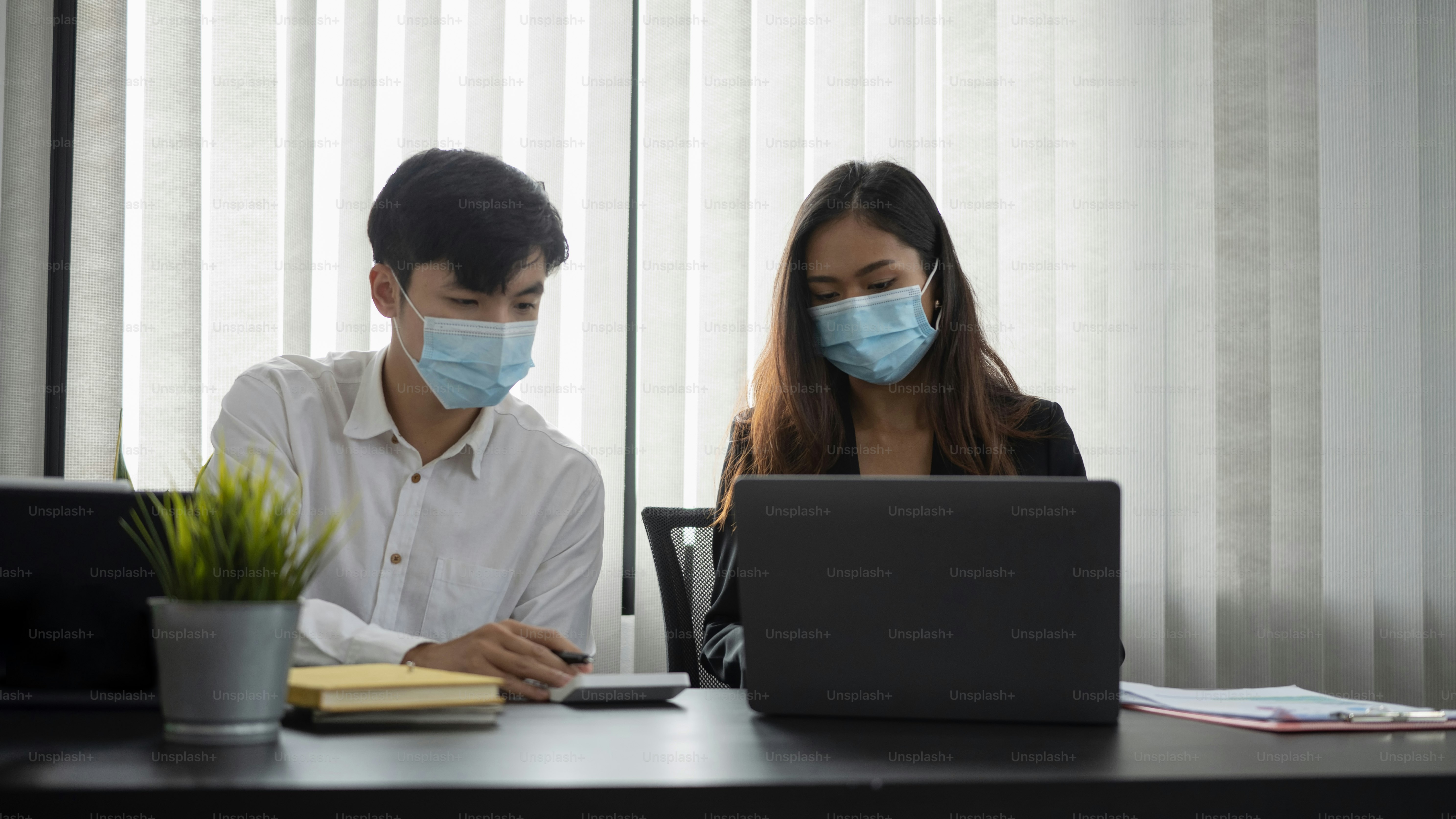 Young asian business people in protective mask discussing business idea and working together in office.