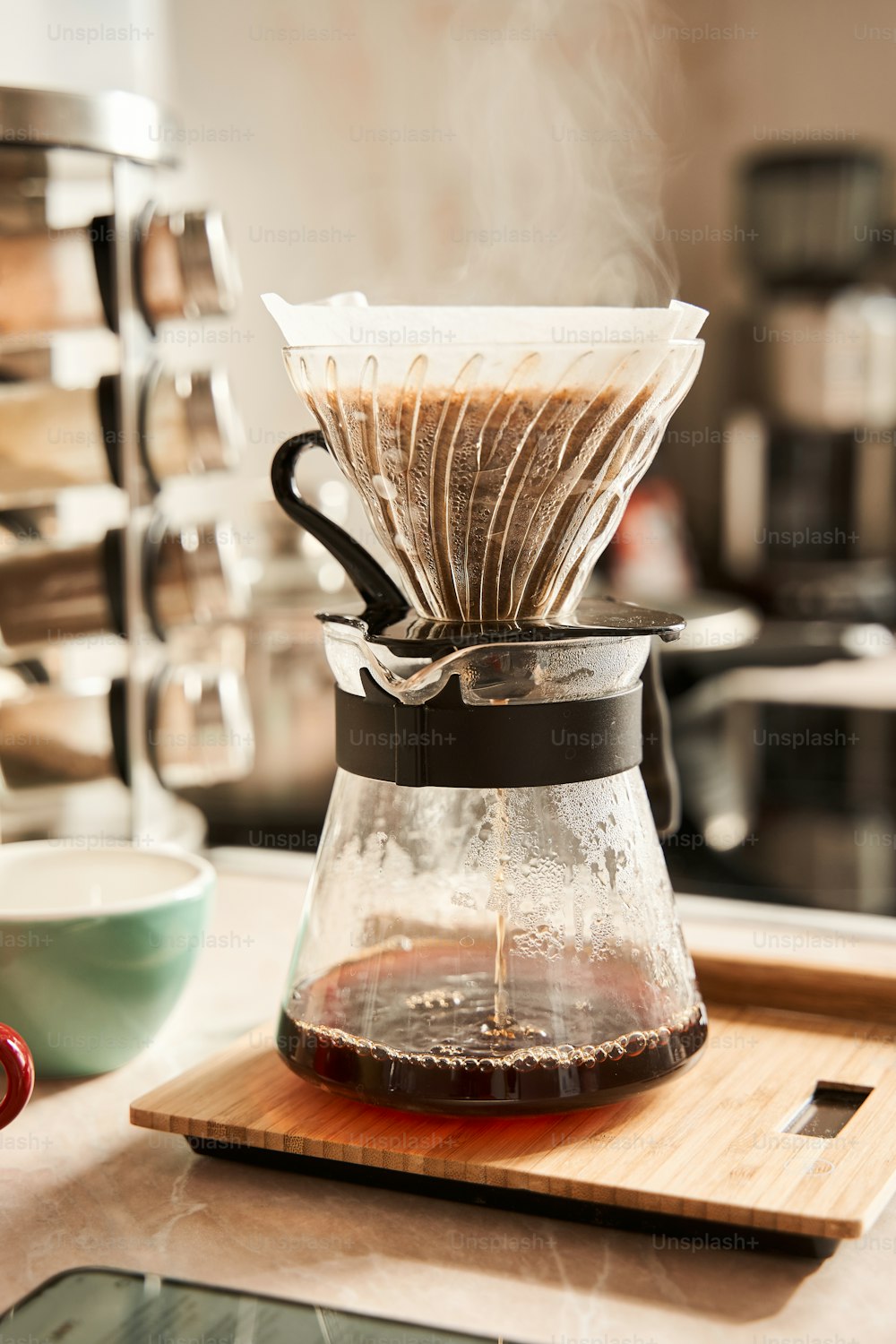 Vertical view of the filter coffee preparing for the breakfast while standing at the table at the kitchen. Steam over the cup. Beverage concept. Stock photo