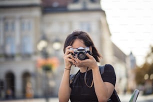 Mujer joven tomando foto en la ciudad con la cámara.