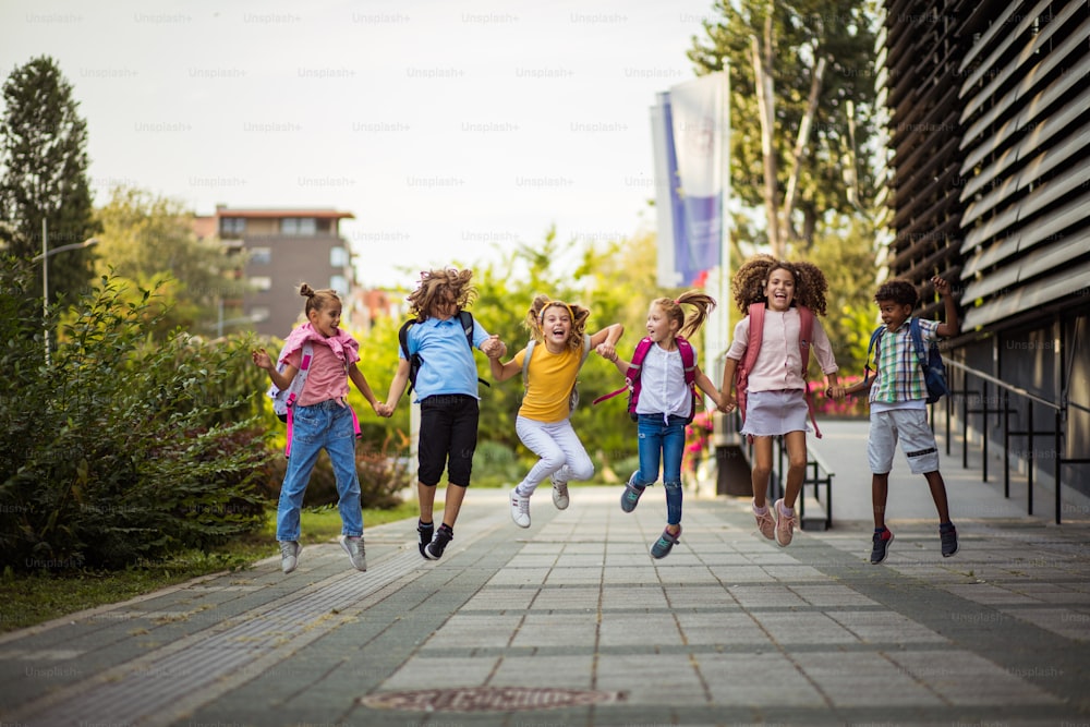 Grupo de escolares em idade fundamental pulando no pátio da escola.