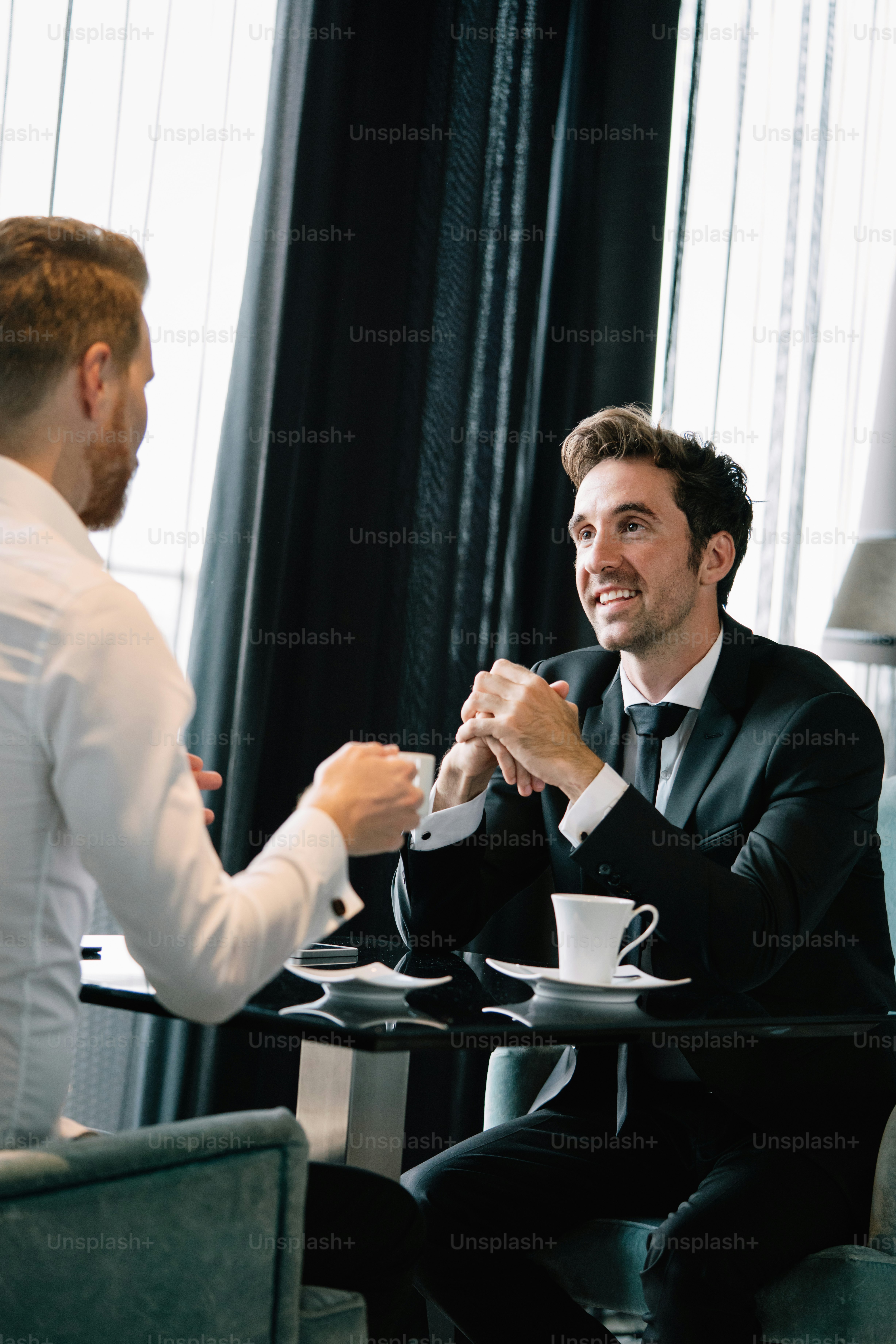 Portrait of successful businessman smiling while discussing deal with partner during meeting at coffee break