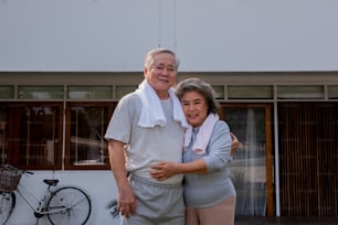 自宅で一緒に運動している幸せなアジアの家族の肖像画。健康な老夫婦は、朝に一緒に屋外運動をします。退職した年配の男性と女性は、自宅でリラックスしてレジャー活動を楽しんでいます