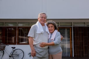 Portrait of Happy Asian family exercising together at home. Healthy senior couple do outdoor workout exercise together in the morning. Retirement elderly man and woman relax and enjoy leisure activity at home