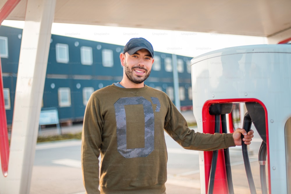 Man pours fuel into his car. Electric pump for car.