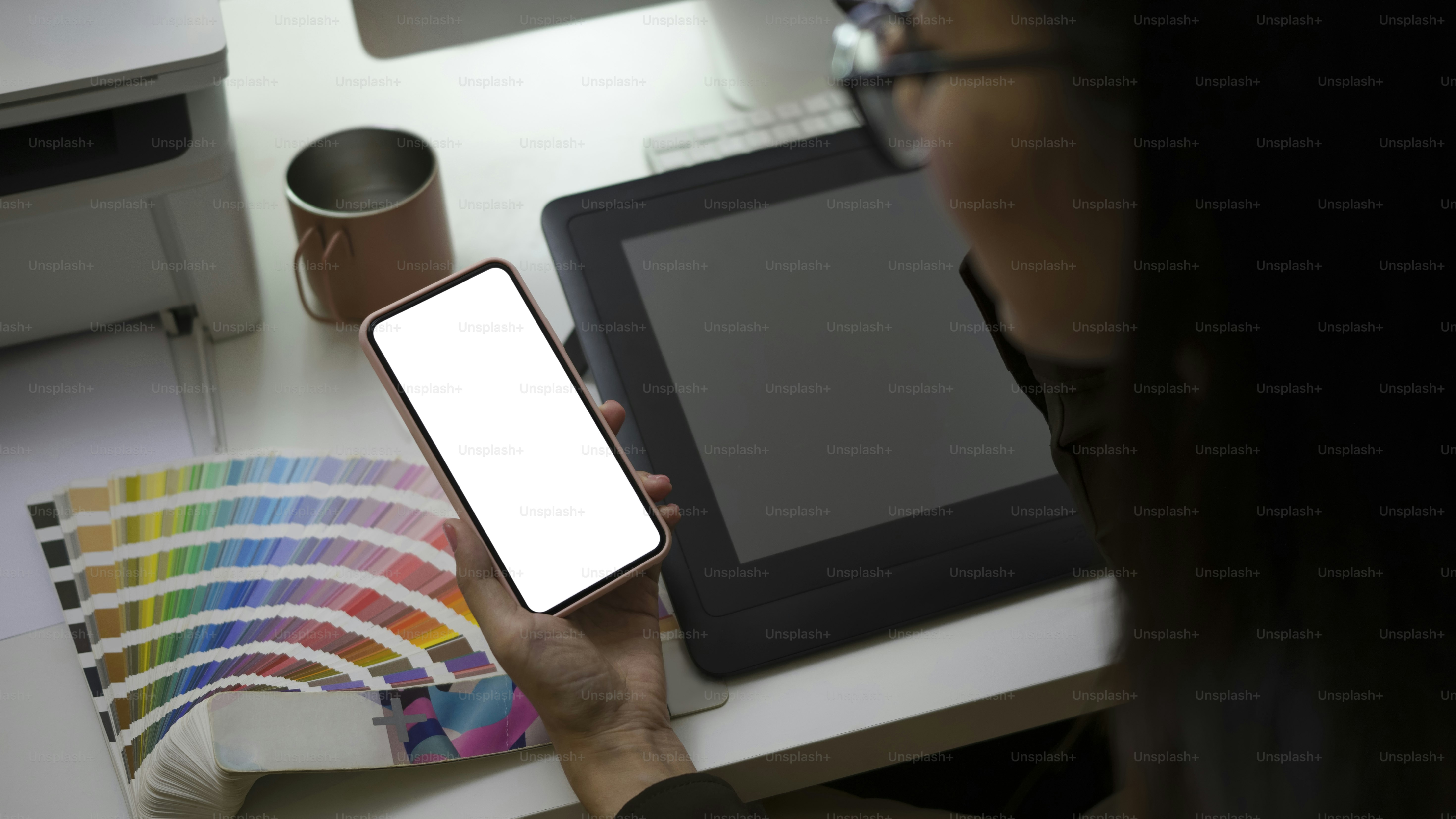Close up view of creative woman sitting at her workplace and using smart phone for texting or massaging with her friends.