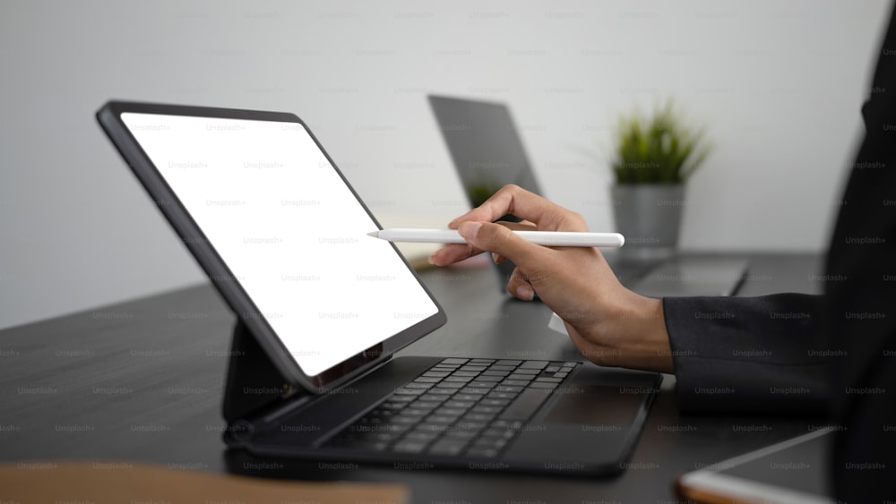 컴퓨터 태블릿의 빈 화면을 가리키는 스타일러스 펜을 들고 있는 사업가 손의 보기를 닫습니다.