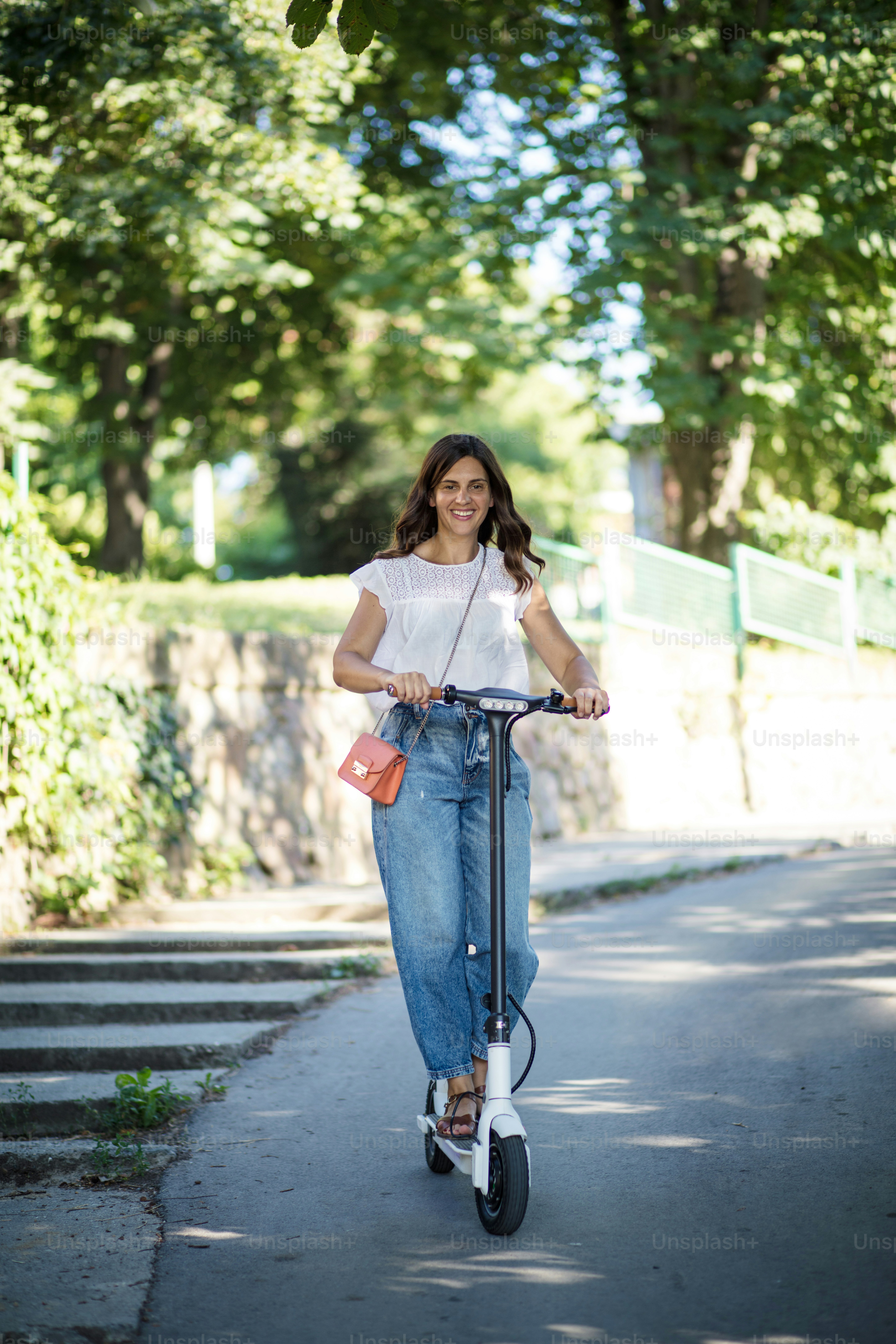 Tempo divertente.  Donna in sella allo scooter al parco.