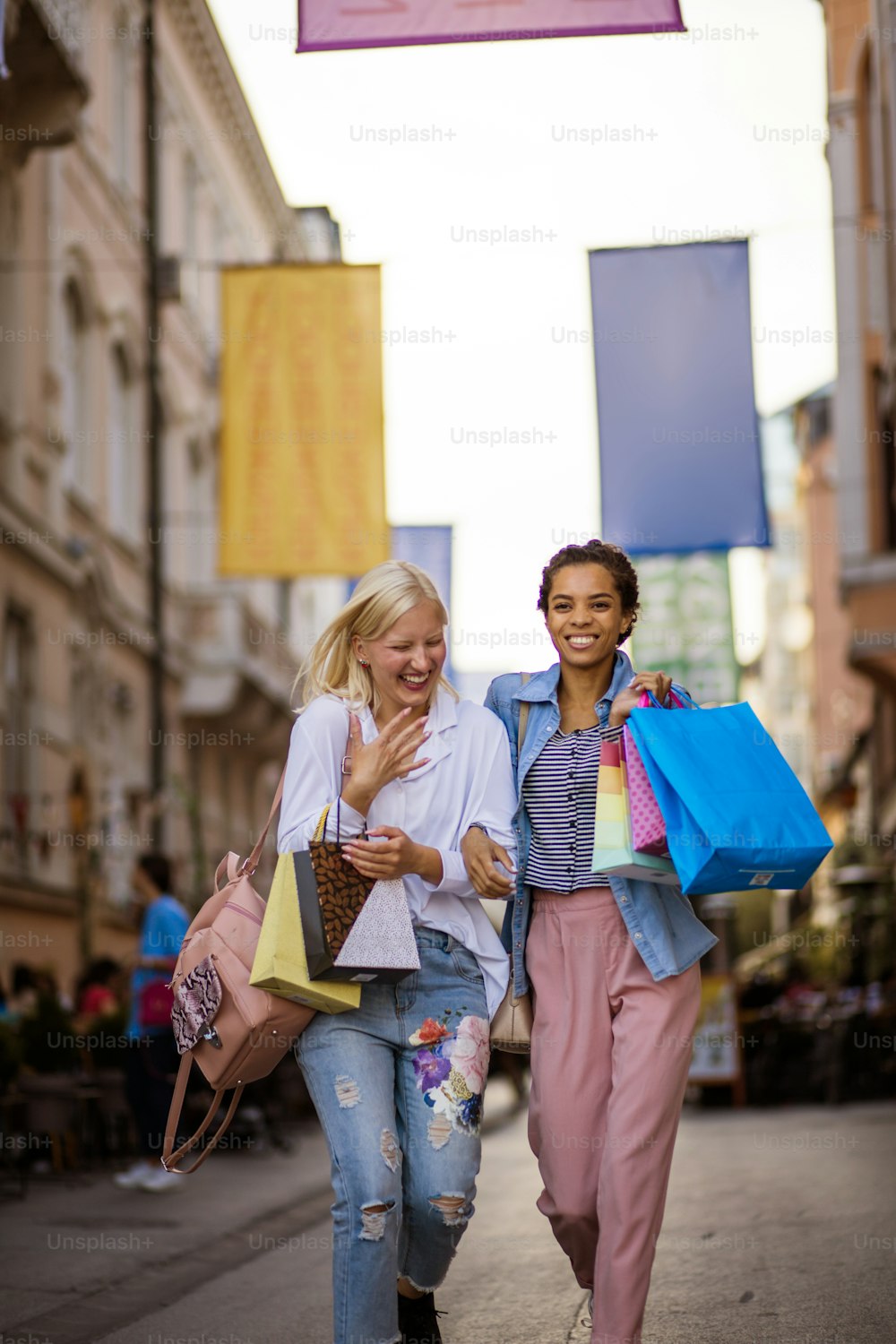 Duas mulheres na rua carregando sacolas de compras.