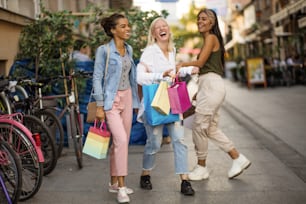 Tre donne per strada con le borse della spesa.