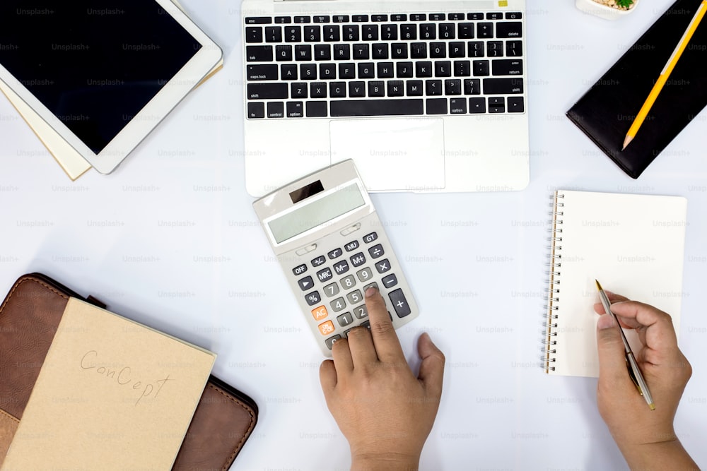 L’homme à l’aide d’une calculatrice et l’écriture prennent des notes avec calculer au bureau et surveiller les informations financières