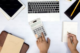 Homem usando calculadora e escrita fazer anotações com cálculo no escritório e Monitoramento de informações financeiras