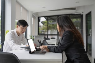 Two young asian businesspeople working together in modern office.
