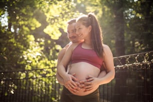 Sports couple standing in the park and touch the stomach.