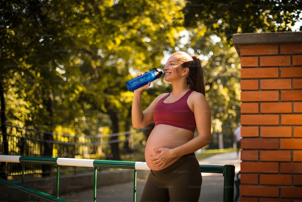 Schwangere Frau trinkt Wasser nach dem Training.