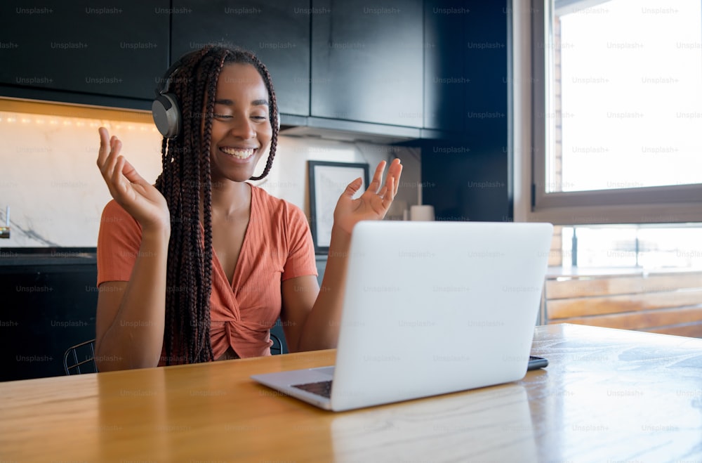 Portrait of a woman on a video call with laptop and headphones while working from home. Home office concept. New normal lifestyle.