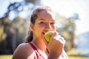 Woman in the park eating apple.