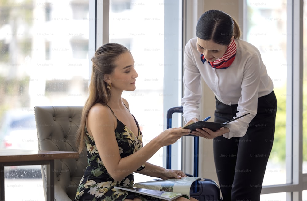 tourist woman going to fill and sign hotel check in registration form at reception counter, kunden service when arrival destination for summer vacation