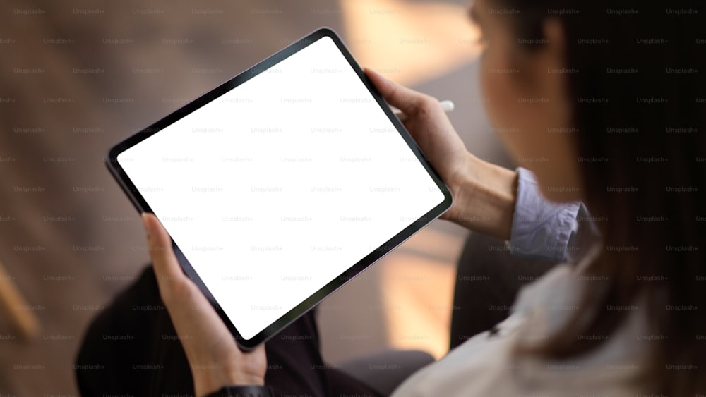 Cropped shot of young businesswoman looking at mock up tablet in office room, clipping path