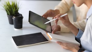 Cropped shot of young business people working together while using tablet in office room