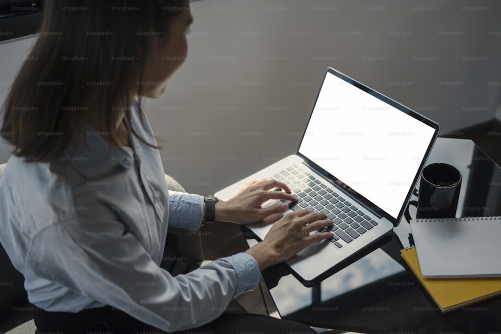 Side view of smiling young female office worker using computer laptop in office.