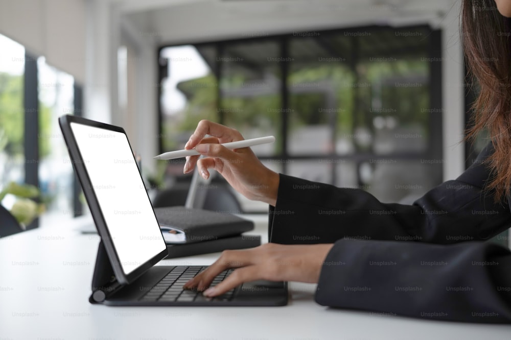Recadré sho d’une femme d’affaires tenant un stylet écrivant des informations sur une tablette d’ordinateur.