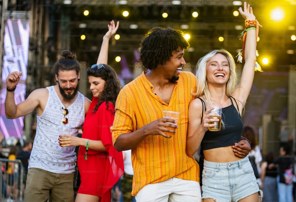 Grupo joven feliz de personas que asisten a festivales en verano, divirtiéndose juntos