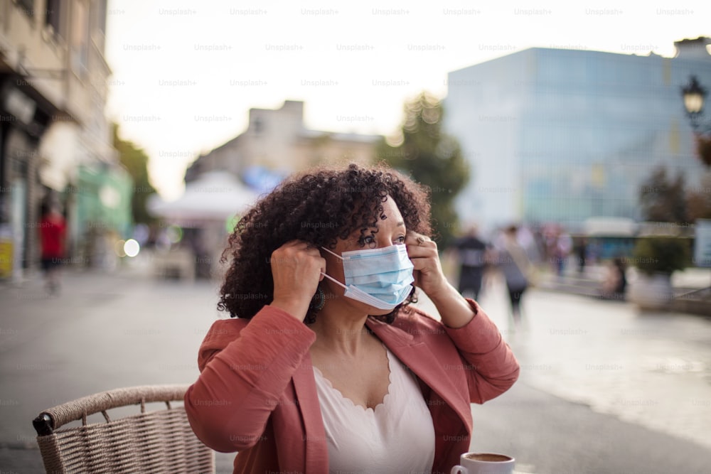 Woman with protective face mask  sitting in café.