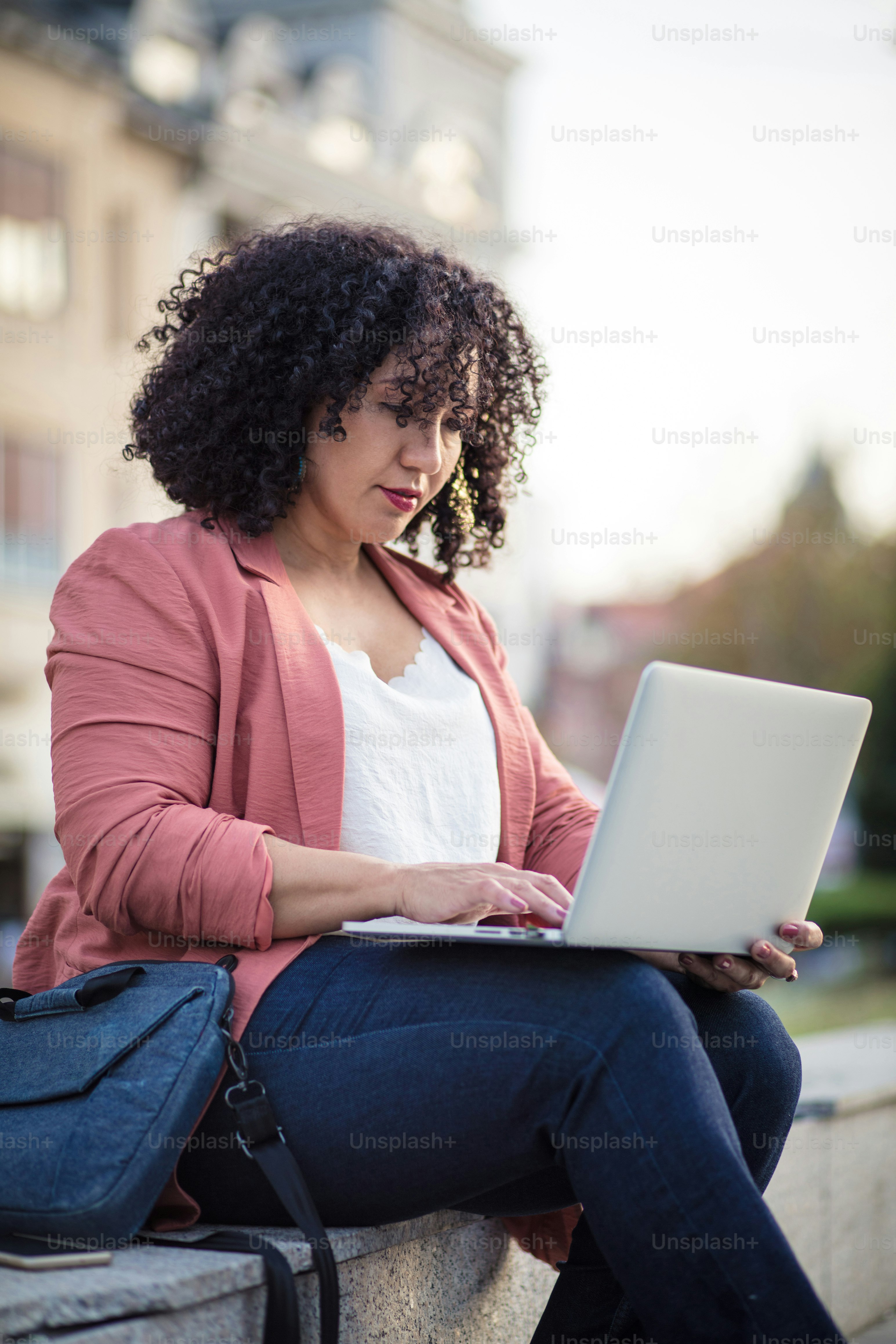 Business woman in the street using laptop.