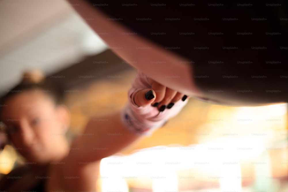 Strong young lady with boxing gloves, punching a punching bag in gym alone. Focus is on hand.