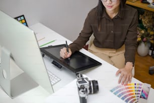 현대 사무실에서 그래픽 태블릿으로 작업하는 창의적인 여성의 자른 샷.