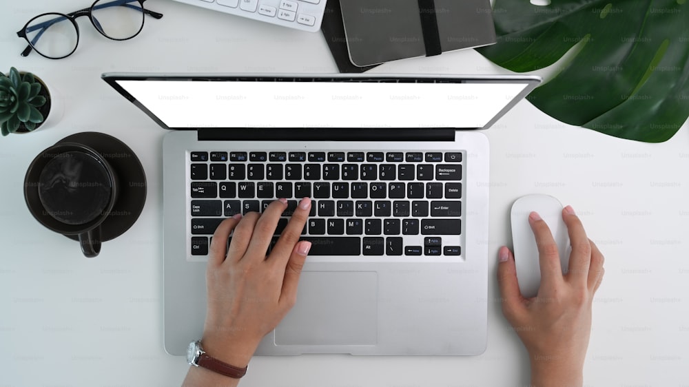 Vue ci-dessus d’une femme travaillant avec un ordinateur portable sur un bureau blanc.