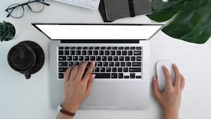 Above view of woman working with computer laptop on white office desk.