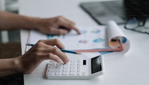 Cierre al hombre de negocios usando la calculadora para el plan de marketing del análisis, el contador calcula el informe financiero, la computadora con el gráfico del gráfico. Conceptos de Negocios, Finanzas y Contabilidad